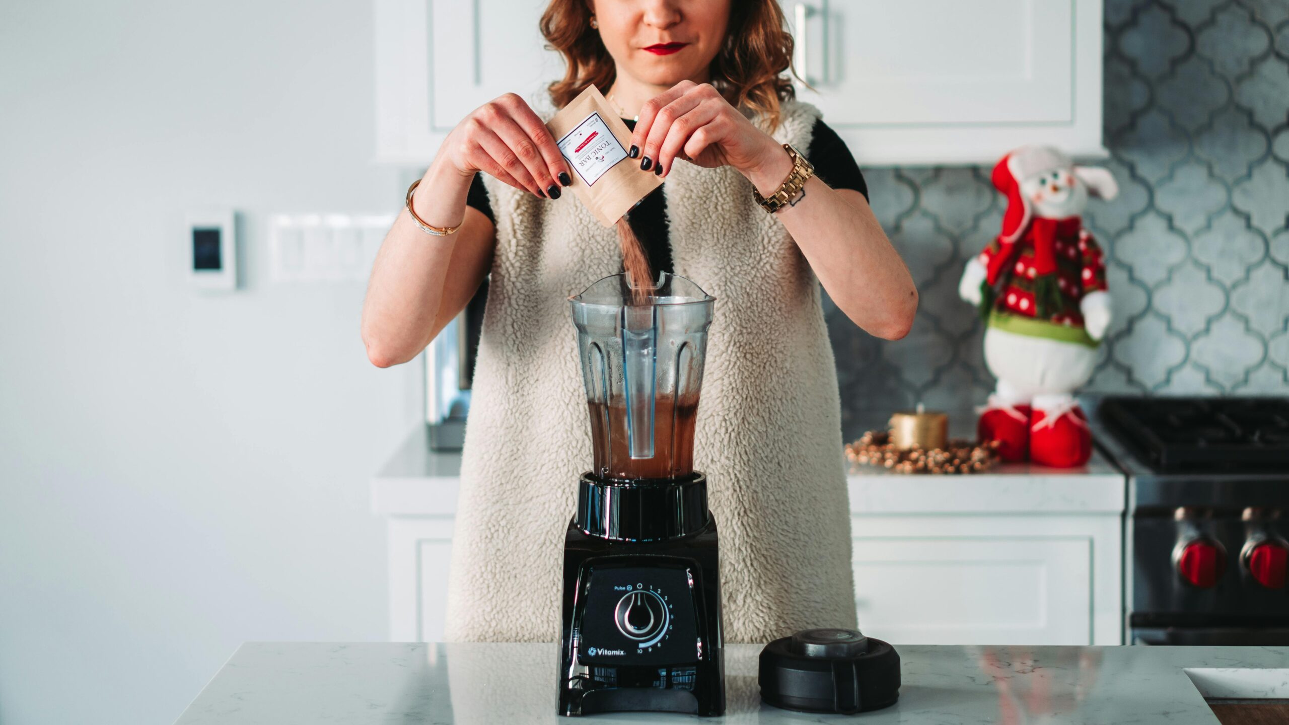 A close-up photo of a kitchen blender loaded with fruits and protein powder
