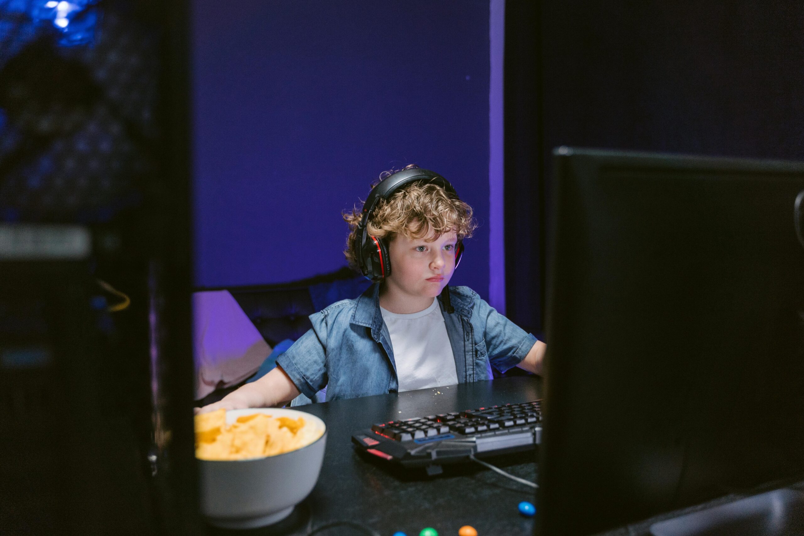 A gamer eating a low-sugar energy bar while playing video games at a desk