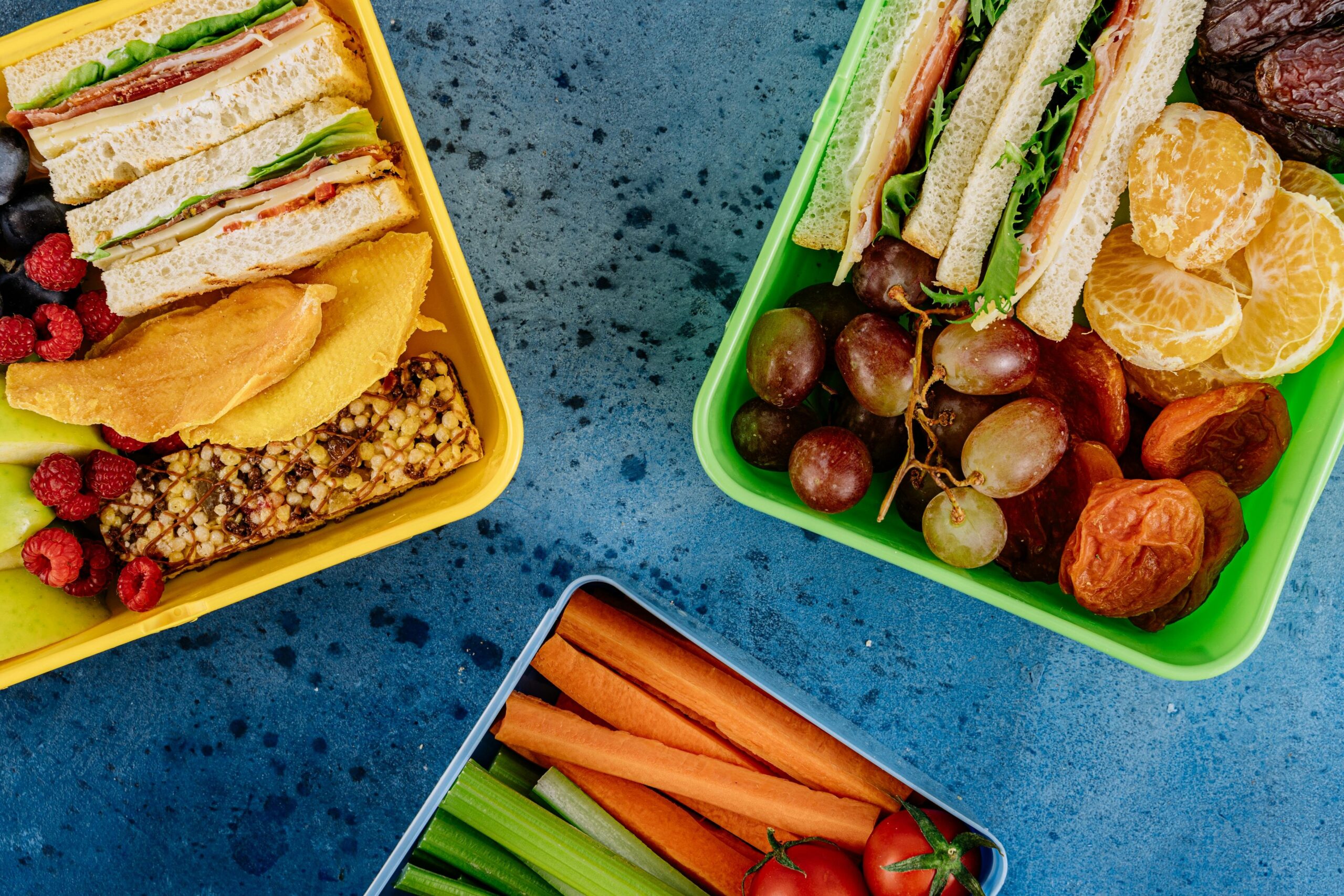 Assorted healthy snacks including almonds, carrot sticks, and hummus next to a controller